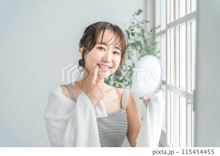 鏡で歯をチェックするアジア人女性（インプラント・ホワイトニング・歯列矯正） 115454455