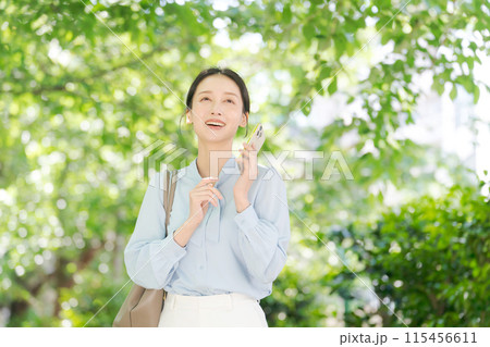 新緑の中で電話をする女性 115456611