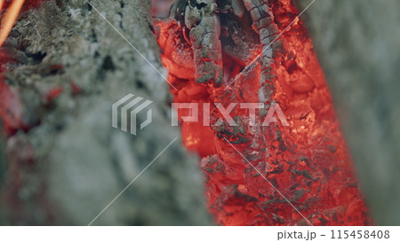 Burning firewood in campfire site. Smoldering and iridescent hot coals. Slow motion. Burning firewood in campfire site. Smoldering and iridescent hot coals. Slow motion. 115458408