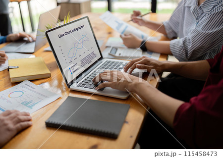 Business Team Discuss Data Analysis with Line Charts Infographic on Laptop in Modern Office Setting 115458473