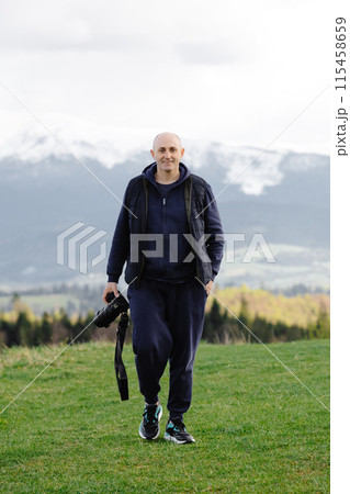 Man hiking with camera in mountain landscape Man hiking with camera in mountain landscape 115458659