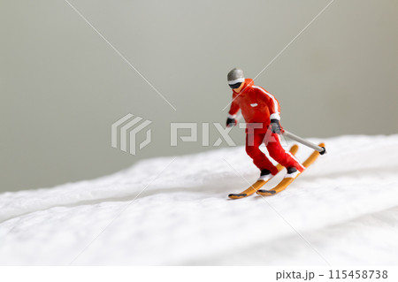 A miniature figurine of a skier dressed in vibrant winter gear. This image is perfect for themes related to winter sports A miniature figurine of a skier dressed in vibrant winter gear. This image is perfect for themes related to winter sports 115458738