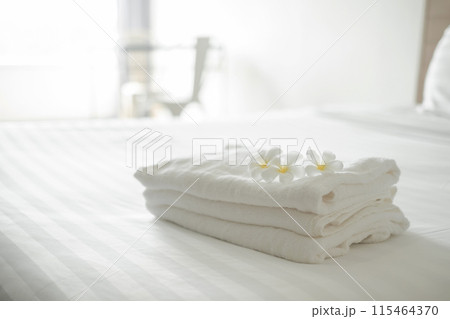 A hotel maid stacked towels on the bed and placed flowers on the towels in a hotel room A hotel maid stacked towels on the bed and placed flowers on the towels in a hotel room 115464370