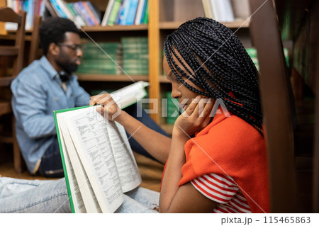 Young people studying in the library together and looking involved Young people studying in the library together and looking involved 115465863