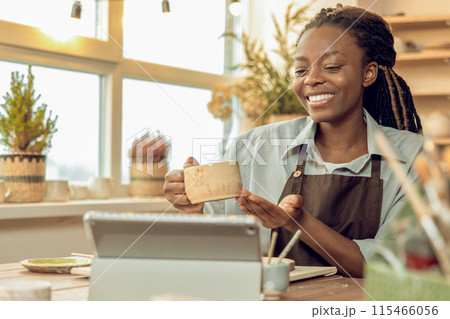 Smiling female sculptor holding a new mug in hands Smiling female sculptor holding a new mug in hands 115466056
