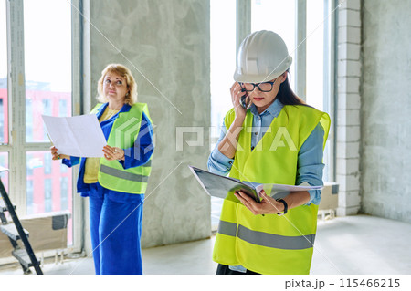 Industrial profession worker female in protective vest helmet working on construction. Industrial profession worker female in protective vest helmet working on construction. 115466215