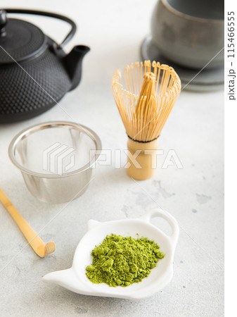 Matcha green tea powder with bamboo spoon and whisk in ceramic bowl with iron kettle Matcha green tea powder with bamboo spoon and whisk in ceramic bowl with iron kettle 115466555