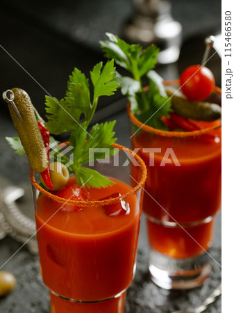Glasses with bloody mary cocktail, cayenne pepper and spicy snacks on dark background. 115466580