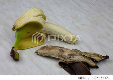 Juicy fresh banana fruit in open yellow peel next to rotten expired banana on white table, ugly brown banana not edible with fresh fruit Juicy fresh banana fruit in open yellow peel next to rotten expired banana on white table, ugly brown banana not edible with fresh fruit 115467421