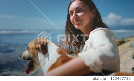 A woman is seated on a rock outdoors, accompanied by two dogs. The woman appears relaxed while interacting with the dogs, who seem attentive and playful. A woman is seated on a rock outdoors, accompanied by two dogs. The woman appears relaxed while interacting with the dogs, who seem attentive and playful. 115467756