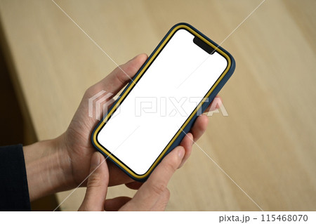 Close up man holding smartphone with blank empty screen sitting in living room 115468070