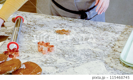 Using an adjustable rolling pin to roll out gingerbread cookie dough on the elegant marble counter in a modern kitchen, getting ready for festive holiday baking. 115468745