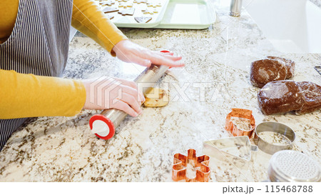Using an adjustable rolling pin to roll out gingerbread cookie dough on the elegant marble counter in a modern kitchen, getting ready for festive holiday baking. 115468788