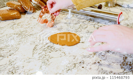 Using various festive cookie cutters, we're cutting out charming gingerbread cookies from the rolled dough on the sleek marble counter, bringing holiday cheer to the modern kitchen. Using various festive cookie cutters, we're cutting out charming gingerbread cookies from the rolled dough on the sleek marble counter, bringing holiday cheer to the modern kitchen. 115468793