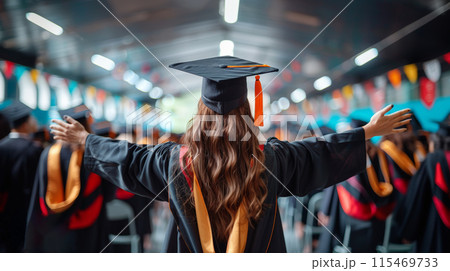 Graduate cap gown, standing with arms outstretched decorated hall during graduation ceremony 115469733