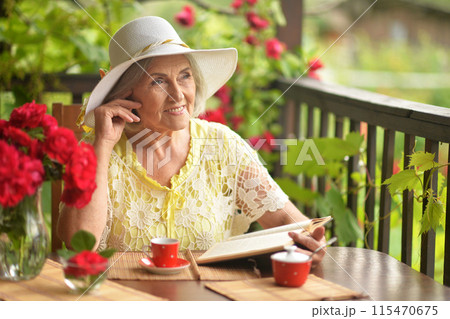 Happy aged woman drinking coffee and talking on phone 115470675