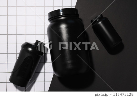 Black plastic jars and bottle on light background, top view 115473129