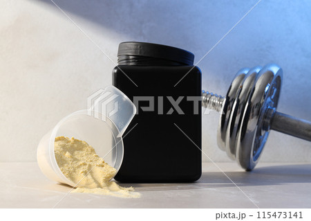 Black plastic jar, measuring cup with powder and dumbbell on light background 115473141