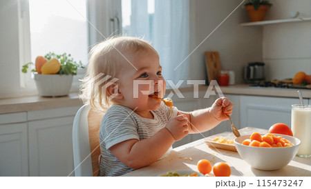 Happy child eats food himself with a spoon. 115473247