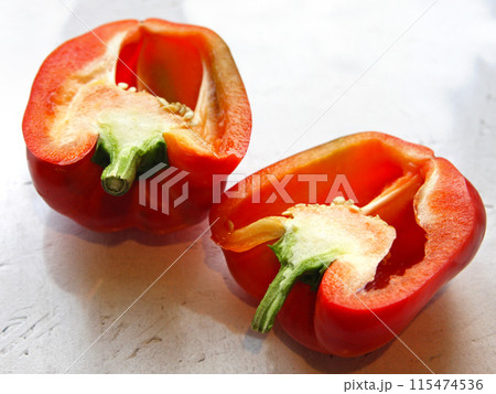 A red pepper, paprika vegetable, cut, lies on a white background, on a table. Proper healthy nutrition, vegetarianism, farming, cuisine, crop production, garden and vegetable garden 115474536