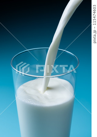 青色の背景でガラスのコップに牛乳を注ぎ入れる 115474603