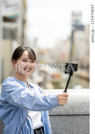 都会の繁華街で自撮り撮影をする若くて可愛い女性｜大阪観光イメージ｜大阪府道頓堀｜戎橋（えびすばし） 115474697