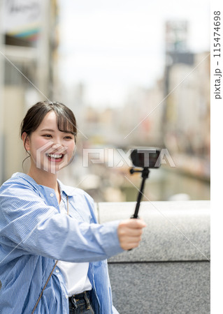 都会の繁華街で自撮り撮影をする若くて可愛い女性｜大阪観光イメージ｜大阪府道頓堀｜戎橋（えびすばし） 115474698
