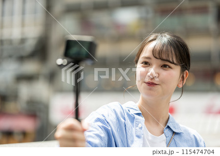都会の繁華街で自撮り撮影をする若くて可愛い女性｜大阪観光イメージ｜大阪府道頓堀｜戎橋（えびすばし） 115474704