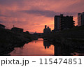 夕焼けに染まる住宅街の川 115474851