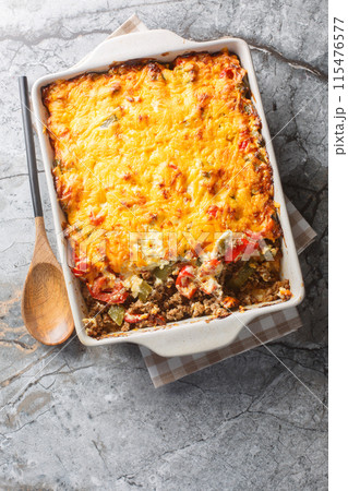 Delicious John Wayne casserole with beef, biscuits, cheese and vegetables close-up in a baking dish. Vertical top view Delicious John Wayne casserole with beef, biscuits, cheese and vegetables close-up in a baking dish. Vertical top view 115476577