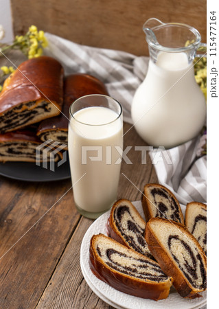 Roll with poppy seeds and a glass of milk. Food on the table. Sweet pastries. Homemade simple yeast bun with filling. Breakfast on a wooden table. lactose and gluten. Roll with poppy seeds and a glass of milk. Food on the table. Sweet pastries. Homemade simple yeast bun with filling. Breakfast on a wooden table. lactose and gluten. 115477164