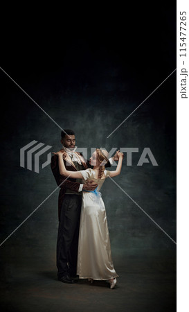 Gentleman and a lady in historical dress engaged in a dance against dark vintage green background. Ballroom event 115477265
