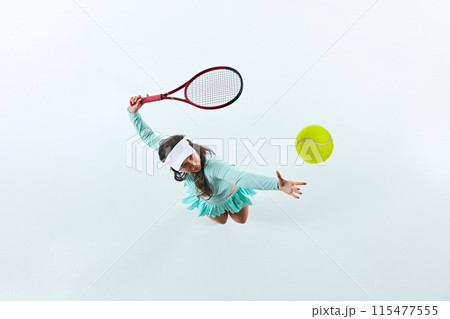 Aerial view of female tennis player, sportsman in mid-action, serving ball against white studio background. 115477555
