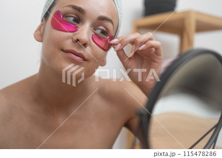 close up woman, applies under-eye patches, actively fighting wrinkles and revitalizing her beauty.  115478286