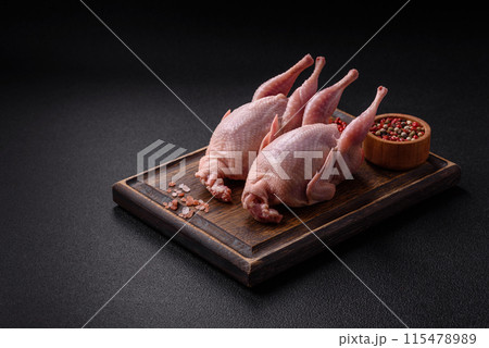 Whole raw quails with salt, spices and herbs on a dark concrete background 115478989