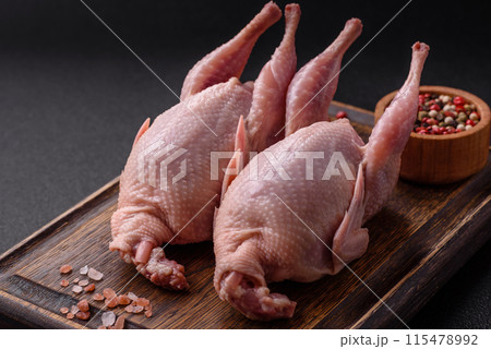 Whole raw quails with salt, spices and herbs on a dark concrete background 115478992