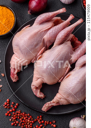 Whole raw quails with salt, spices and herbs on a dark concrete background Whole raw quails with salt, spices and herbs on a dark concrete background 115479009