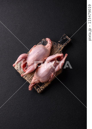 Whole raw quails with salt, spices and herbs on a dark concrete background 115479019