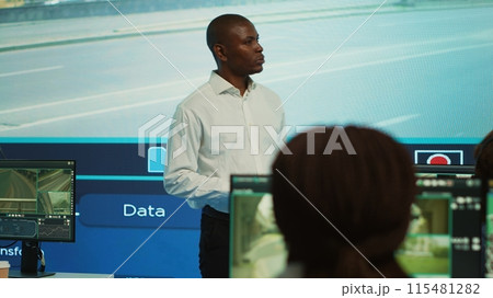 Team leader supervising his employees monitoring the traffic, diverse people employing surveillance camera in the city. Control center tracking radar footage via CCTV security system. Camera A. Team leader supervising his employees monitoring the traffic, diverse people employing surveillance camera in the city. Control center tracking radar footage via CCTV security system. Camera A. 115481282