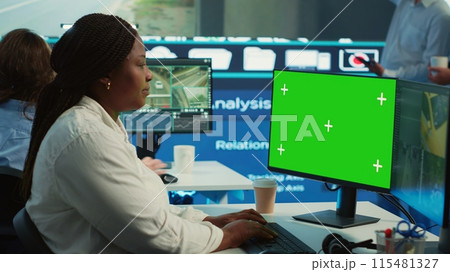 African american operator works with isolated display and satellite map, guiding the delivery truck driver to arrive at shipment location pin. Employee helps with heavy traffic on CCTV. Camera A. 115481327