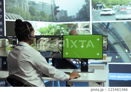 Indian specialist monitoring traffic surveillance next to a greenscreen display, gather intelligence on traffic activity in the city. Government employee collecting data on cars, plate recognition. 115481366
