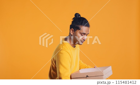 Portrait of man holding thermal backpack, crossing arms, ready to fulfill orders, studio backdrop. Calm food delivery service worker prepared to do delivery to customers, camera B 115481412