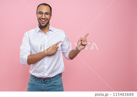 Happy cheerful man in white shirt pointing at empty space for promotion 115481689