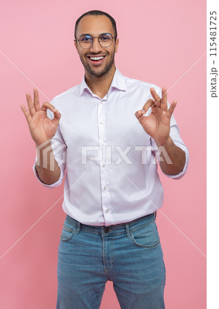 Satisfied man in white shirt showing okay gesture Satisfied man in white shirt showing okay gesture 115481725