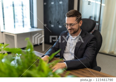 Man sitting at his desk in the office and working on laptop 115481790