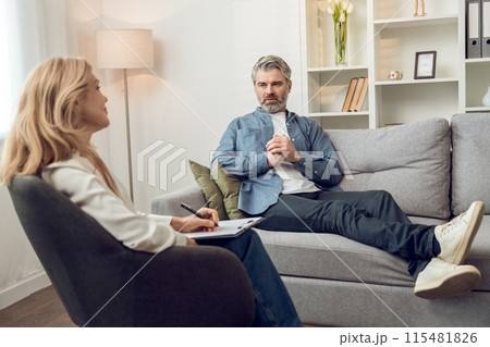 Woman psychologist discusses solutions and support with her troubled male patient in office 115481826