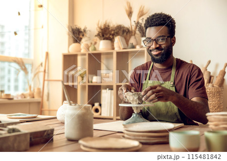 African american young man working with clay in pottery studio 115481842