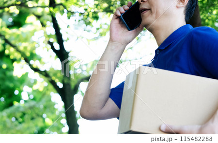 荷物とスマートフォンを持つ男性の手元 115482288