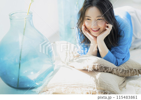 仰向けに寝転がる青い服の女性 115483861
