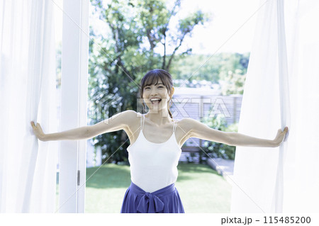 レースのカーテンを開ける活発な若い女性 115485200